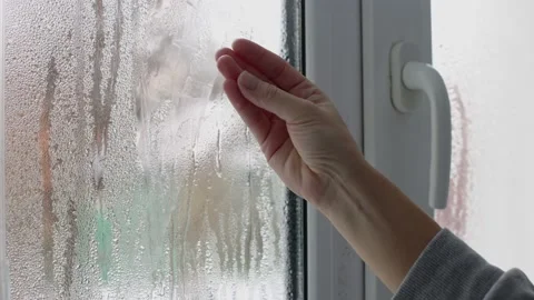 A womans hand touching wet window glass with water drops of condensation. 4K. Stock Footage 230619702