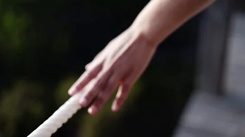 Woman's hand touching a white rope while walking on a wooden walkway. Stock Footage 115079094
