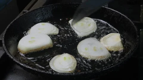 A woman's hand turns fried onions in a frying pan with oil with a knife. Me.. 库存影片 282905241