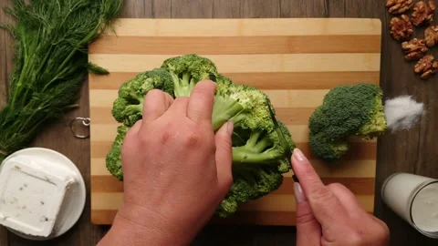 A woman's hand turns over the broccoli and begins to cut it Stock Footage 234057294