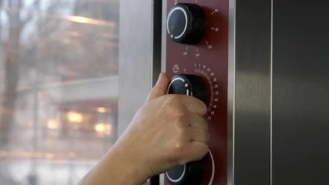 The woman's hand turns on the time button on the electric oven. Stock Footage 257418783