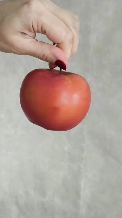 A womans hand twists a red apple, holding it by a branch. Juicy fruits. Stock Footage 325774260