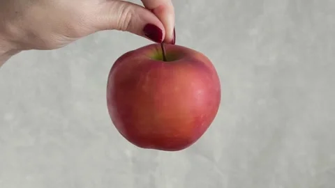 A womans hand twists a red apple, holding it by a branch. Juicy fruits. Stock Footage 325774262
