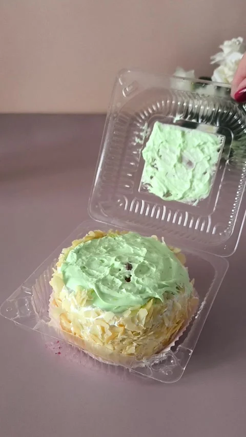 A womans hand twists a transparent plastic container with a pie on the table, a Stock Footage 324697959