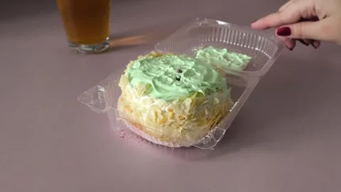 A womans hand twists a transparent plastic container with a pie on the table, a Stock Footage 324698099