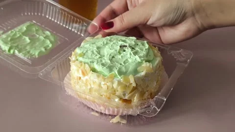 A womans hand twists a transparent plastic container with a pie on the table, a Stock Footage 324698227