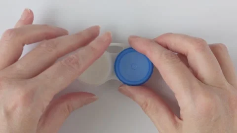 Woman's hand unscrews the left lid of a contact lens container Stock Footage 337182306