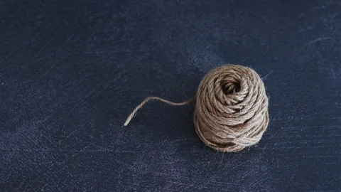Woman's hand untangling ball of thread by pulling string and making it roll Video stock 116646439