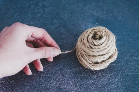 Woman's hand untangling ball of thread by pulling string Foto stock