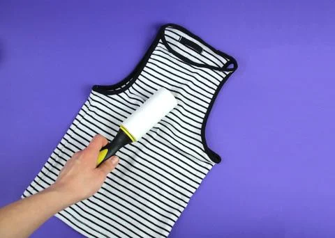 Woman's hand using a clothes roller to keep her T-shirt clean Fotos de archivo