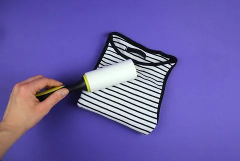 A woman's hand using a clothes roller to keep a folded T-shirt clean Stock Photos