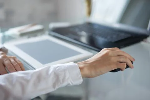 Woman's hand using cordless mouse on glass table Foto stock