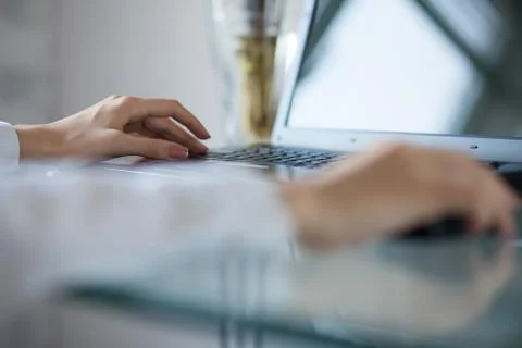 Woman's hand using cordless mouse on glass table Foto stock