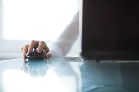 Woman's hand using cordless mouse on glass table Foto stock