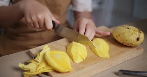 Woman's hand using knife to cut ripe mango on wooden cutting board. Stock-Footage 308219050