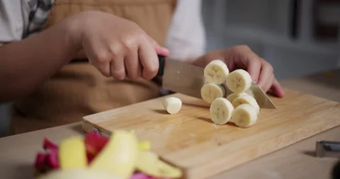 Woman's hand using knife to cut bananas to prepare to make dessert on the table Видео 308220329