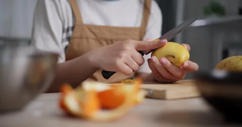 Woman's hand using knife to peel ripe mango on wooden table. Stockbeeldmateriaal 308218203