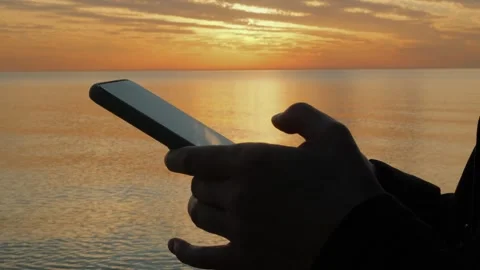 Woman's hand using mobile phone by the sea at sunset. Stock Footage 314811607
