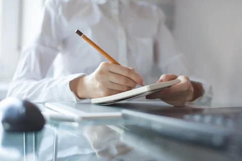 Woman's hand using a pencil noting on notepad Stock Photos