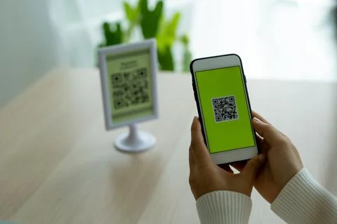 The woman's hand is using the phone to scan the qr code to select the food me Foto stock