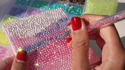 Woman’s hand using a pink bedazzling tool to decorate box Vídeo Stock 343423350