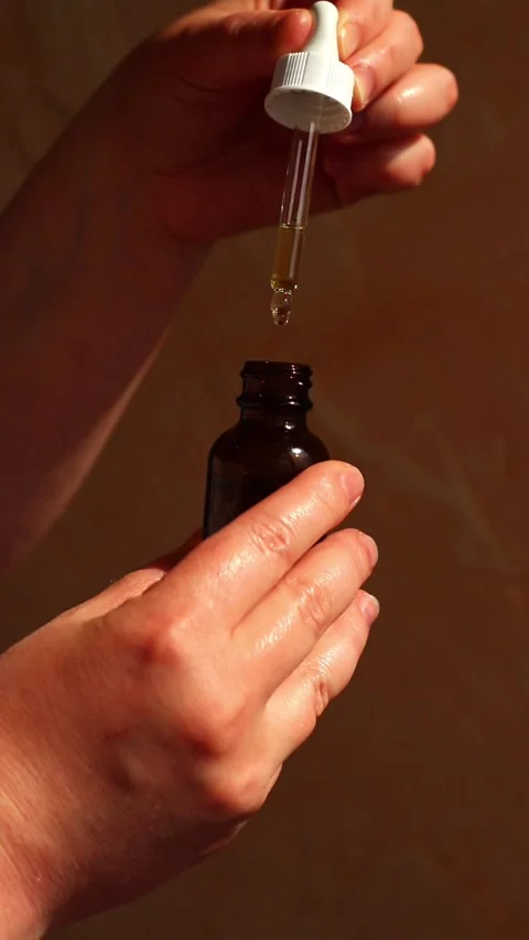 Womans hand using pipette to dispense luxury facial oil on neutral background Stock Footage 311447052