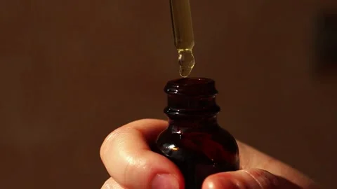 Womans hand using pipette to dispense luxury facial oil on neutral background Stock Footage 311447060