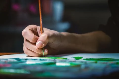 Woman's hand using small brush to paint picture on white paper Stock Photos