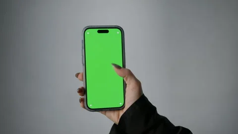 A woman's hand is viewing content on a smartphone with a green screen Stock Footage 267821343
