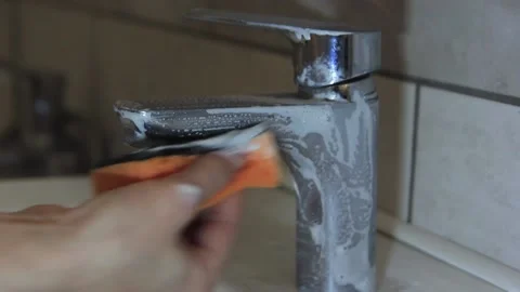 A woman's hand washes the tap with a sponge and detergent. Video stock 145891331