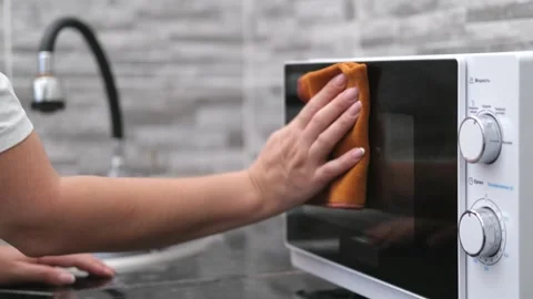 A woman's hand washes a white microwave oven in the kitchen Stock-Footage 277691289