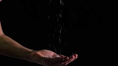 Woman's hand on which salt falls from above.Black background, slow motion Stock Footage 199252482