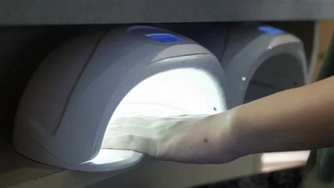 Woman's hand while put into the uv nail dryer for gel polish on nails in ha.. Stock Footage 249665333