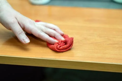 Woman's hand wipes a table with a red microfiber cloth, showcasing effectiv.. Foto stock