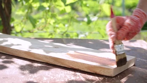 A woman's hand in a work glove paints the board with a protective impregnation Stock Footage 161111038