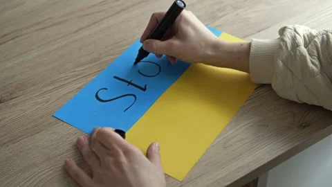 Woman's hand writes on the background of the Ukrainian Flag STOP PUTIN. Stock Footage 170958831