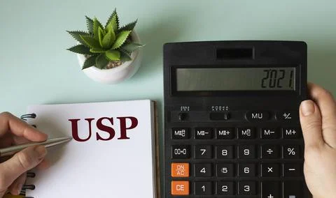 A woman's hand writes in a notebook the acronym USP on the background of a ca Stock Photos