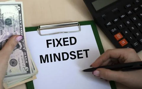 A woman's hand writes in a notebook the words FIXED MINDSET on the background Stock Photos