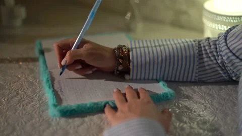 A woman's hand writes with a pen in a notebook. close-up. 4k footage. raw Stock Footage 153464943