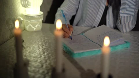 A woman's hand writes with a pen in a notebook at night.. close-up. 4k footage Stock Footage 153526037