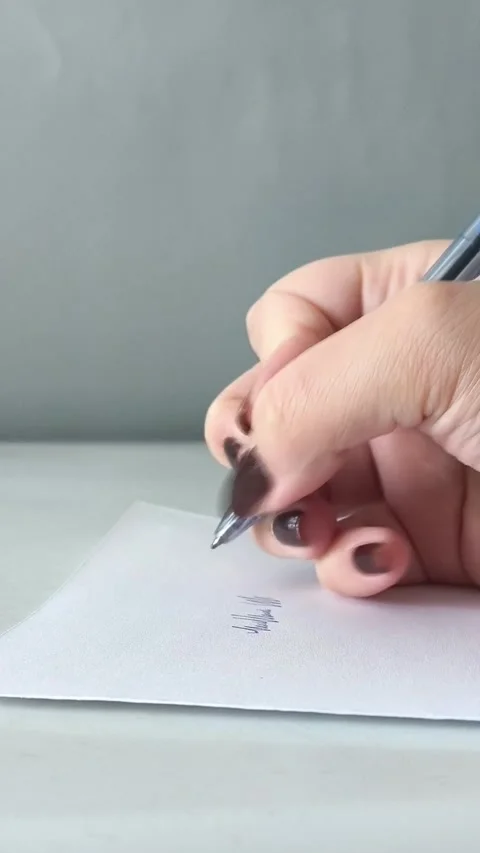 A womans hand writes with a pen on a piece of paper in close-up. Exams, tests at Vidéo 330156723