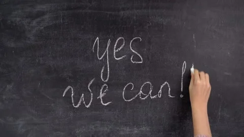 A woman's hand writes the phrase YES WE CAN on a chalkboard Stock Footage 164134880