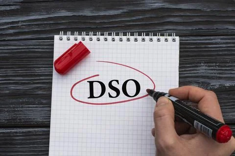 A woman's hand writes on a white sheet the word DSO on a black wooden backgro Stock Photos