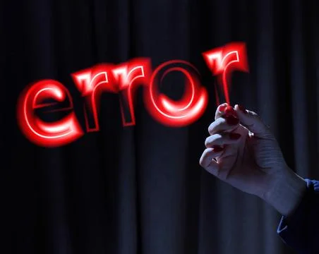A woman's hand writes the word error in red neon light in the air against a.. Stock Photos