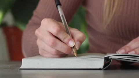 Woman's hand writing on notebook Stock Footage 166025318