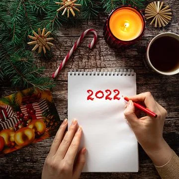 Woman's hand writing on a notepad sheet in Christmas setting Stock Photos