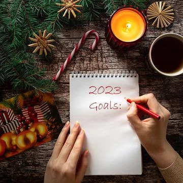 Woman's hand writing on a notepad sheet in winter holiday setting Stock Photos