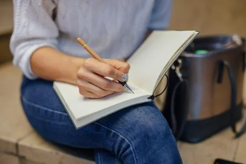 Woman's hand writing something at the notebook. Indoor background. Stock Photos