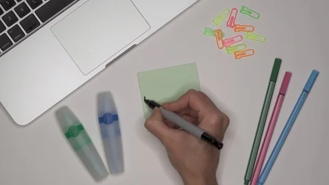 Womans hand writing UNIVERSITY on notepad. Laptop and stationery on the table. Stock Footage 101961184