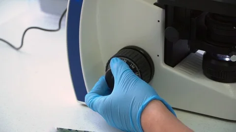 A womans hand zooming in the microscope lense. Close-up view. Stock Footage 119768100